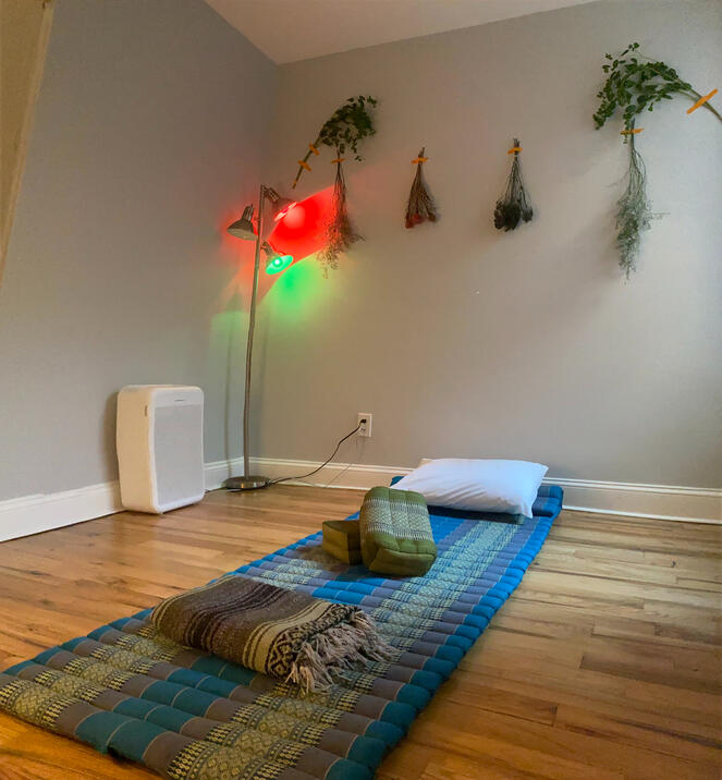 Photo of bule and green thai massage mat rolled out in the session space. There is a HEPA Filter in the photo as well as dried flowers hanging on the walls